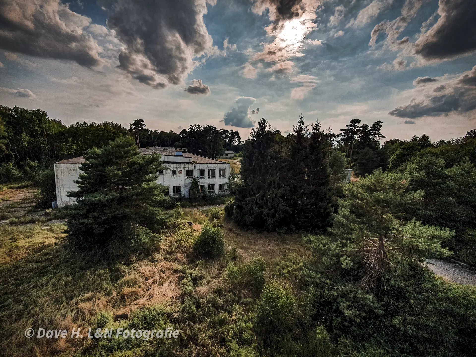 Blick von oben über das verwaiste Gelände mit Büschen und Häusern.