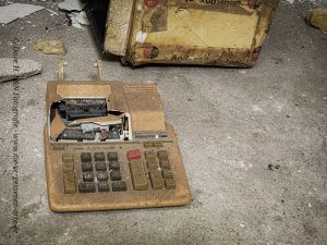 Staubüberzogen steht eine alte Kasse auf dem Boden des ehemaligen Hotels.