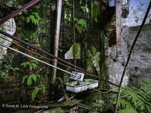 An einer mit Grünspan überzogenen Wand der alten Tuchfabrik hängt noch ein altes Waschbecken.