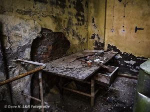 Zerbrochen und leicht eingefallen befindet sich eine Werkbank in einem verlassenem Gebäude.