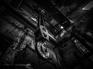 von der Decke hängend ein großer, rostiger Haken eines Kranes.