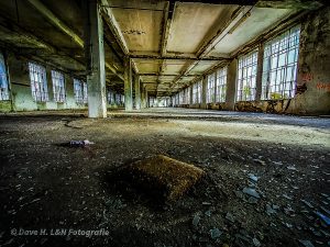 Leere, weitläufige Halle einer verlassenen Produktionsstätte.