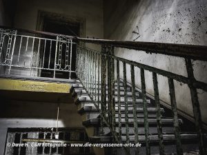 Am Geländer einer alten Treppe blättert die Farbe ab.