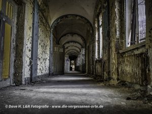 Ein langer dunkler Gang mit Gewölbedecke führt durch das verlassene Waldhaus Sanatorium.
