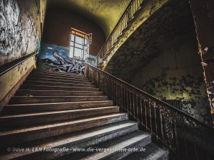 Die Treppe hinauf fotografiert, am Ende befindet sich ein Fenster.