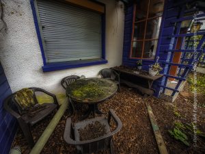 Eine Sitzecke mit vermoostem Tisch und ein paar Stühlen im verlassenen, alten Zollhaus.