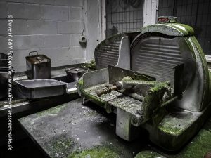 Aufschnittmaschine, überwachsen mit Moos, steht in der Küche von dem verlassenen Kurhotel.