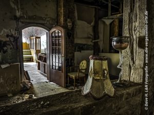 Blick vom Tresen in den Gastraum des verlassenen Kurhotels, auf dem Tresen steht noch ein alter Lampenschirm.