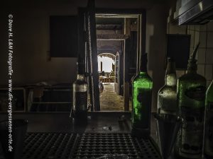 Blick vom Tresen zum Gastraum, Fotografiert zwischen zwei noch auf dem Tresen befindlichen Flaschen.