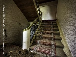 Uriger Teppich verziert die verstaubte Treppe des verlassenen Gebäudes.