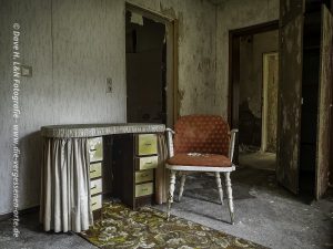 Mit Grünspan überzogener Stuhl und Schreibtisch in Zimmer des verlassenen Kurhotels.