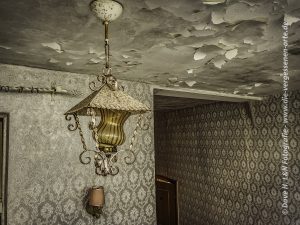 Alte Lampe, überzogen von Staub, in einem Zimmer des verlassenen Kurhotels.