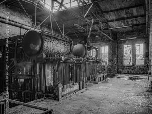 Heizkessel in einer großen Halle eines Heizkraftwerkes, von oben erstrahlt die Sonne durch das Dach.