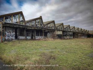 Die Werkshallen der verlassenen DDR-Industrie schmücken den Platz mit ihren Spitzdächern.