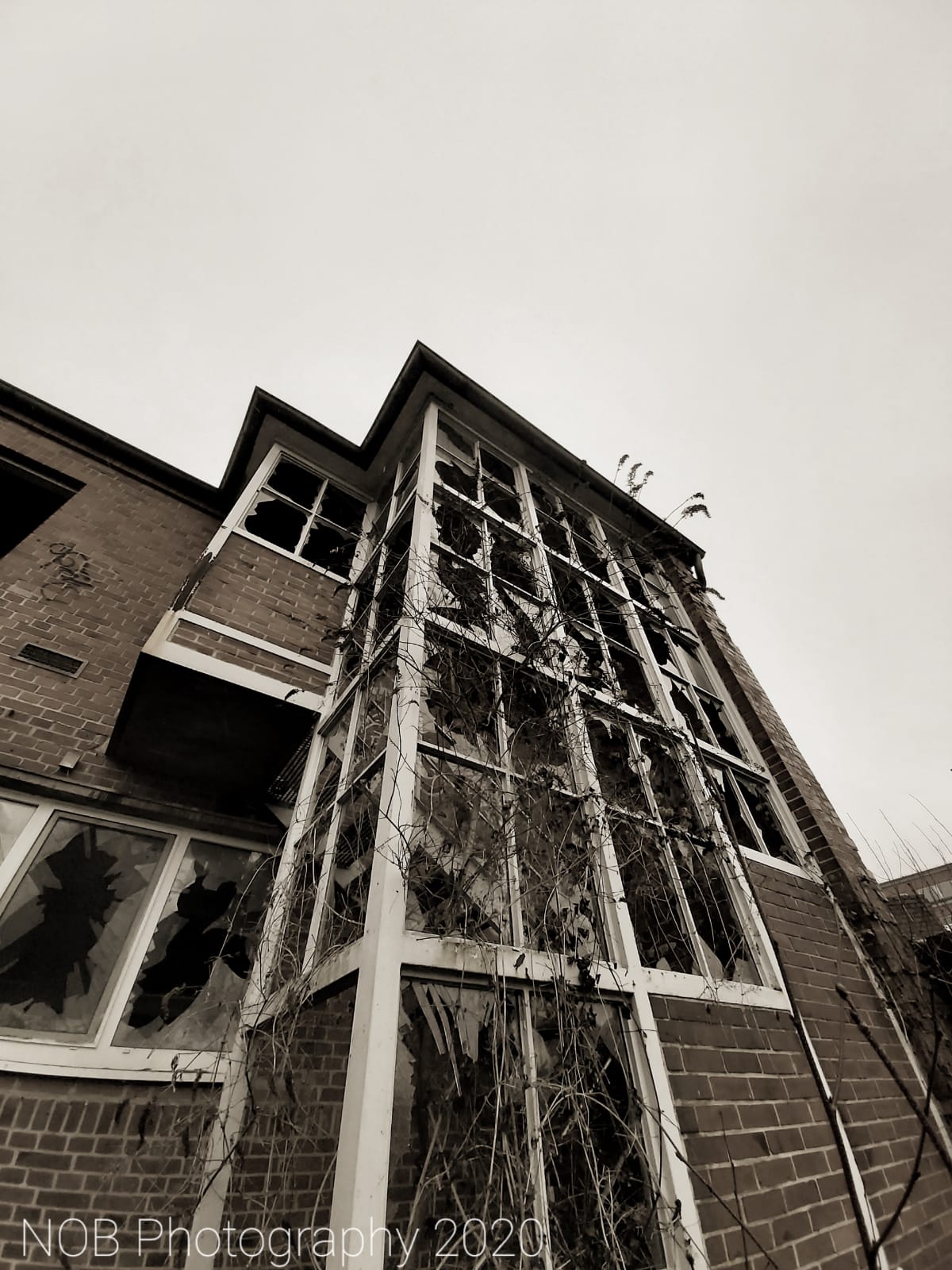 Das Fabrikgebäude von außen, Eingeschmissene Scheiben sind das Zeichen von Vandalismus.