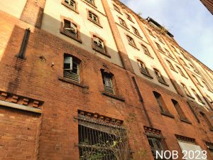 Die Fassade der verlassenen Industrieruine, man sieht die Fenster und vielen Stockwerke des Gebäudes.