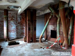 Eine Halle in der verlassenen Industrieanlage, hinten rechts sieht man einen verrosteten großen Kessel stehen.