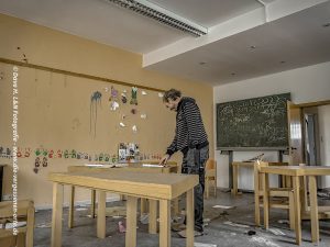 Urbex Ausrüstung und Sicherheit für Lost Places Fotografie: Nils liest in einer verlassenen Schule etwas auf einem Zettel durch.