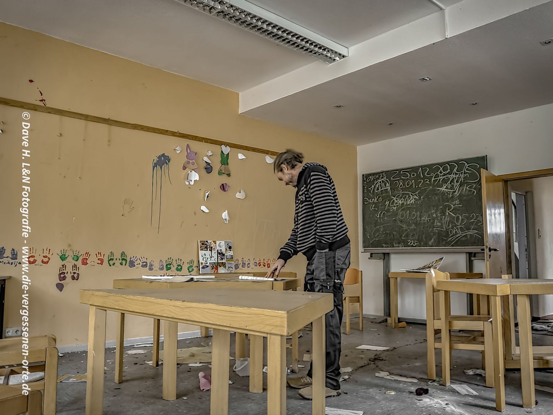 Urbex Ausrüstung und Sicherheit für Lost Place Fotografie: Nils liest in einer verlassenen Schule etwas auf einem Zettel durch.
