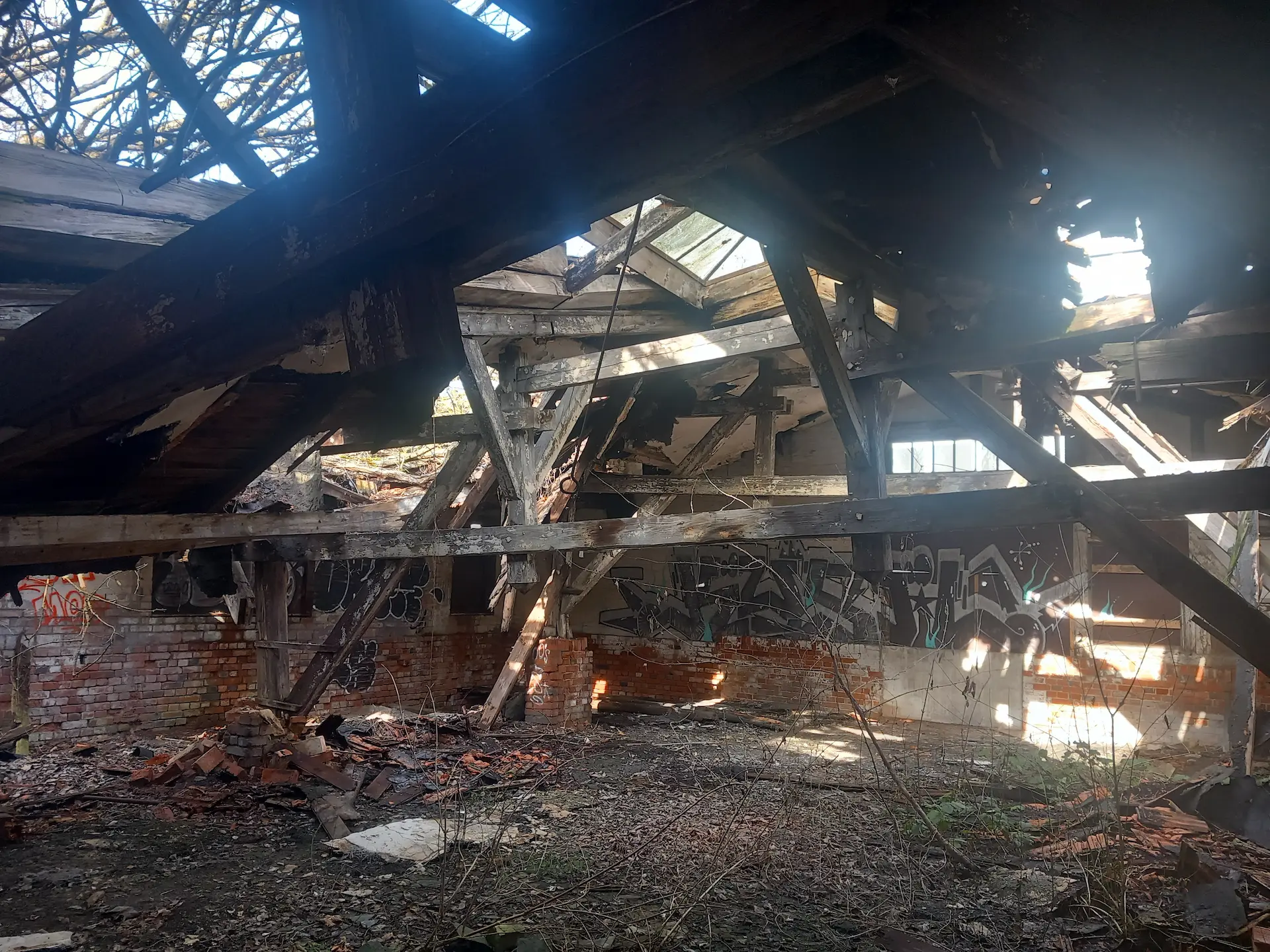 Deckenbalken hängen in die Halle der ehemaligen jüdischen Schuhfabrik hinunter.