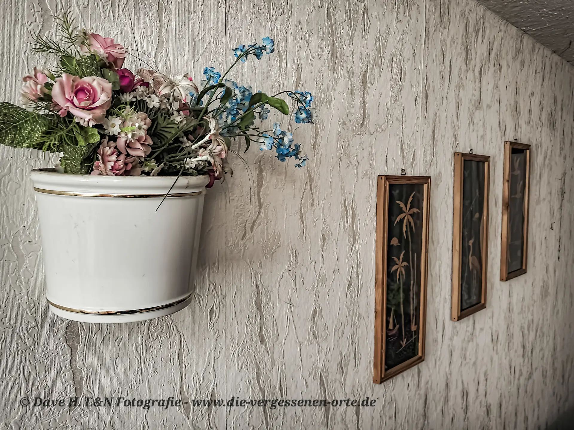 Bilder aus alten Tagen befinden sich an der Wand und schmücken das verlassene Wohnzimmer aus.