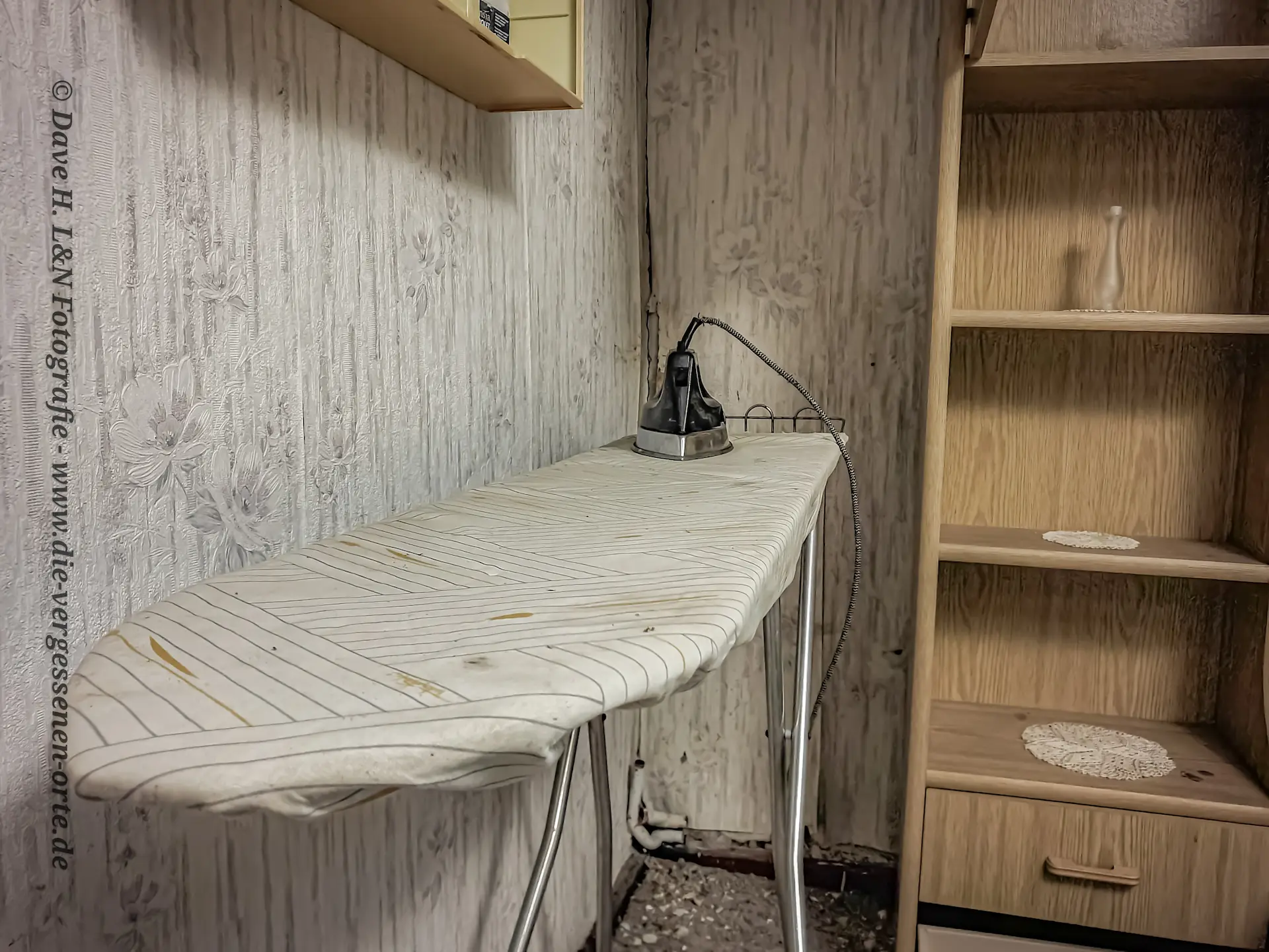 Ein Bügelbrett im Schlafzimmer des einstigen Wohnhauses wird von Staub benetzt.