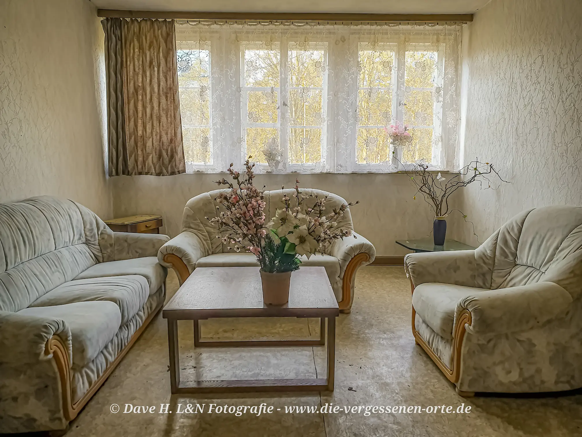 Sitzecke mit Stoff-Couchgarnitur und Tisch im verlassenen Schloss.