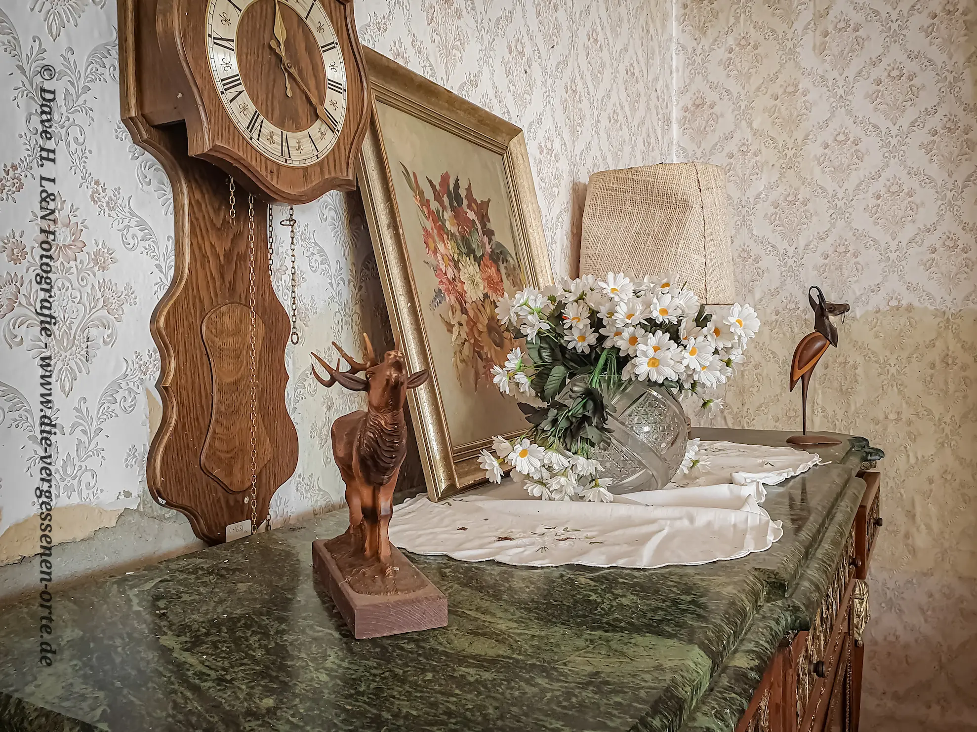 Kommode mit Marmorplatte, Uhr und Blumenvase im ehemaligen Schloss.