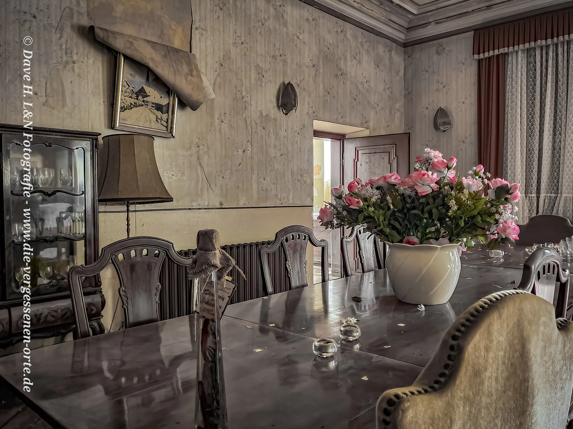 Gedeckte Speisetafel im alten Anwesen mit Blumenstrauß im Mittelpunkt.