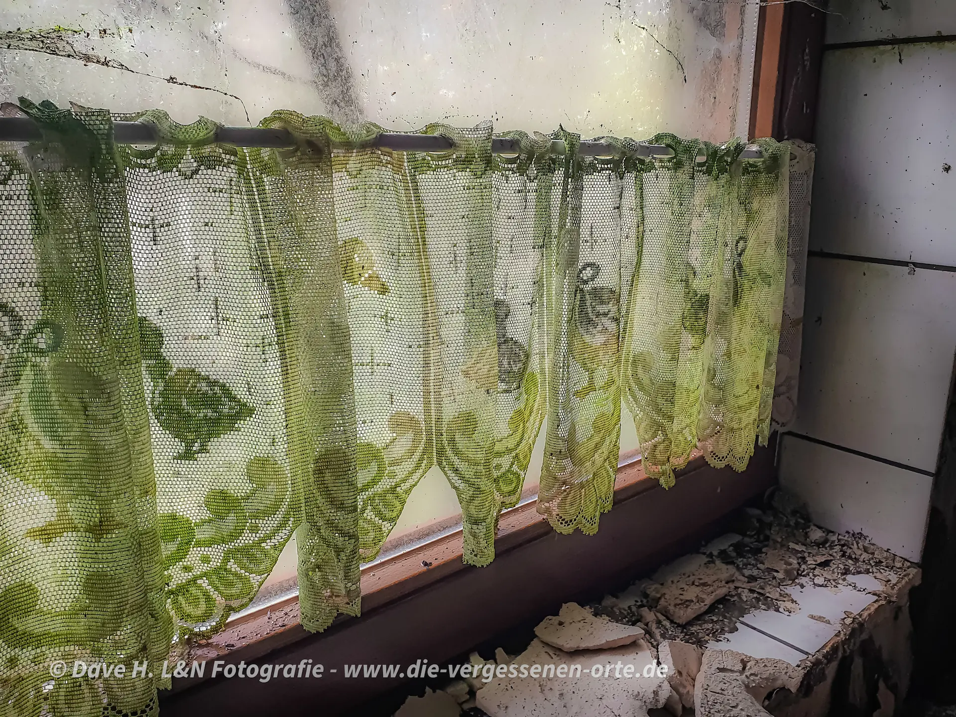 Grünspanüberzogene Gardine an einem Fenster.