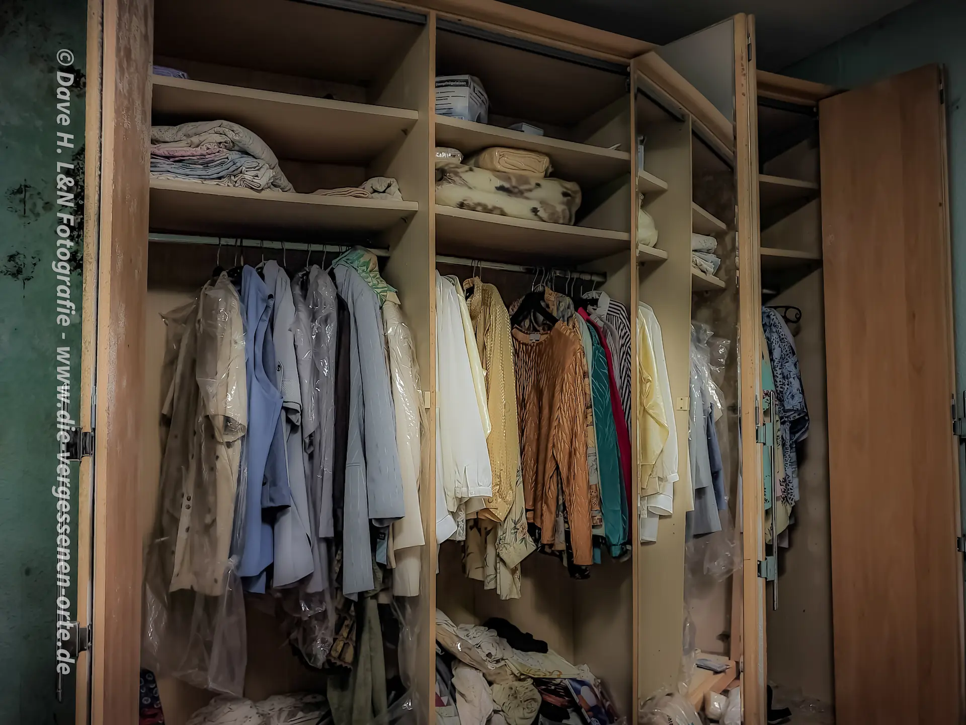 Kleider hängen in einem Schrank des ehemaligen Landhauses.