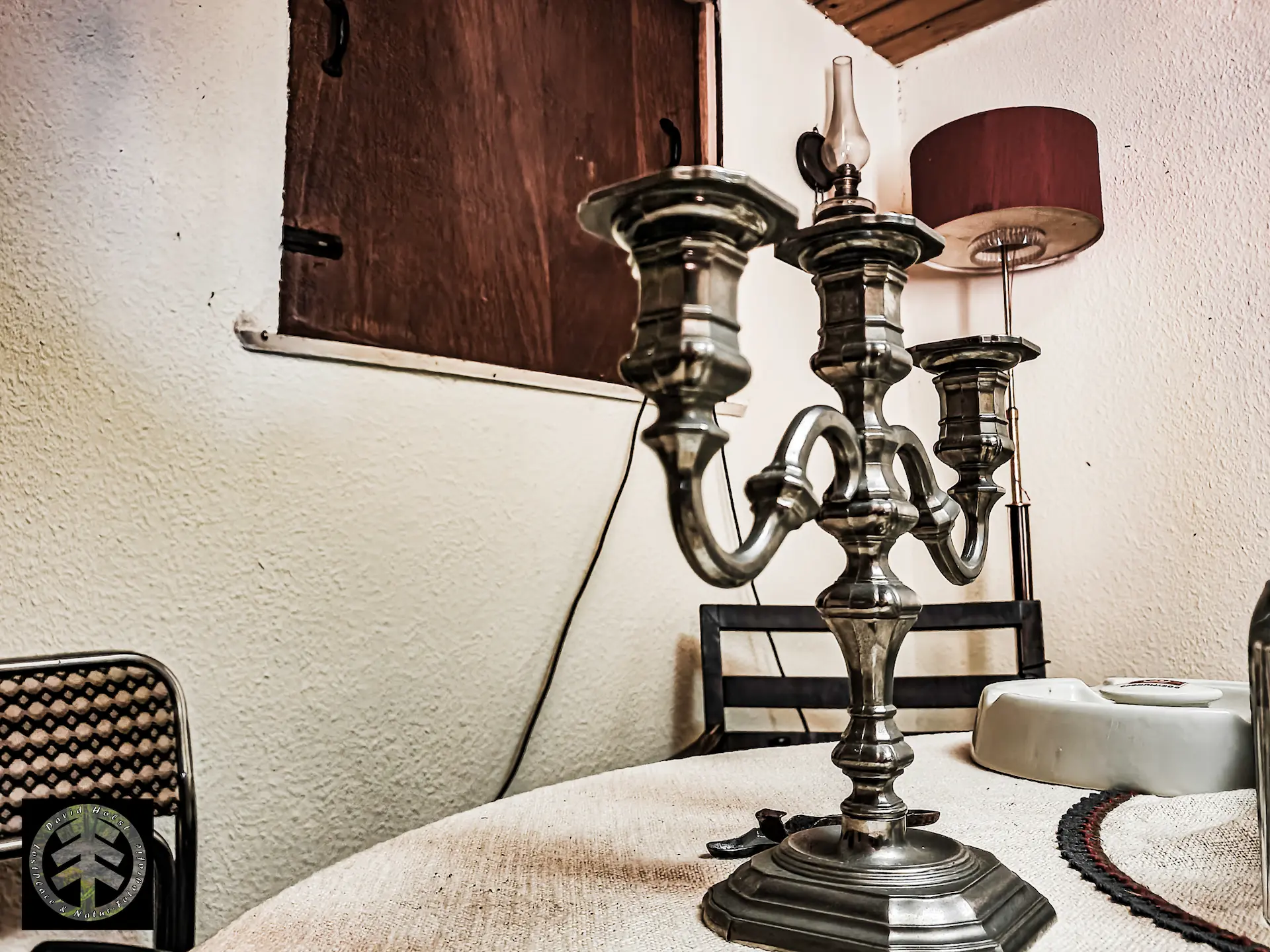 Verlassenes Wochenendhaus: Im Aufenthaltsraum steht ein uriger Kerzenständer auf dem Tisch.