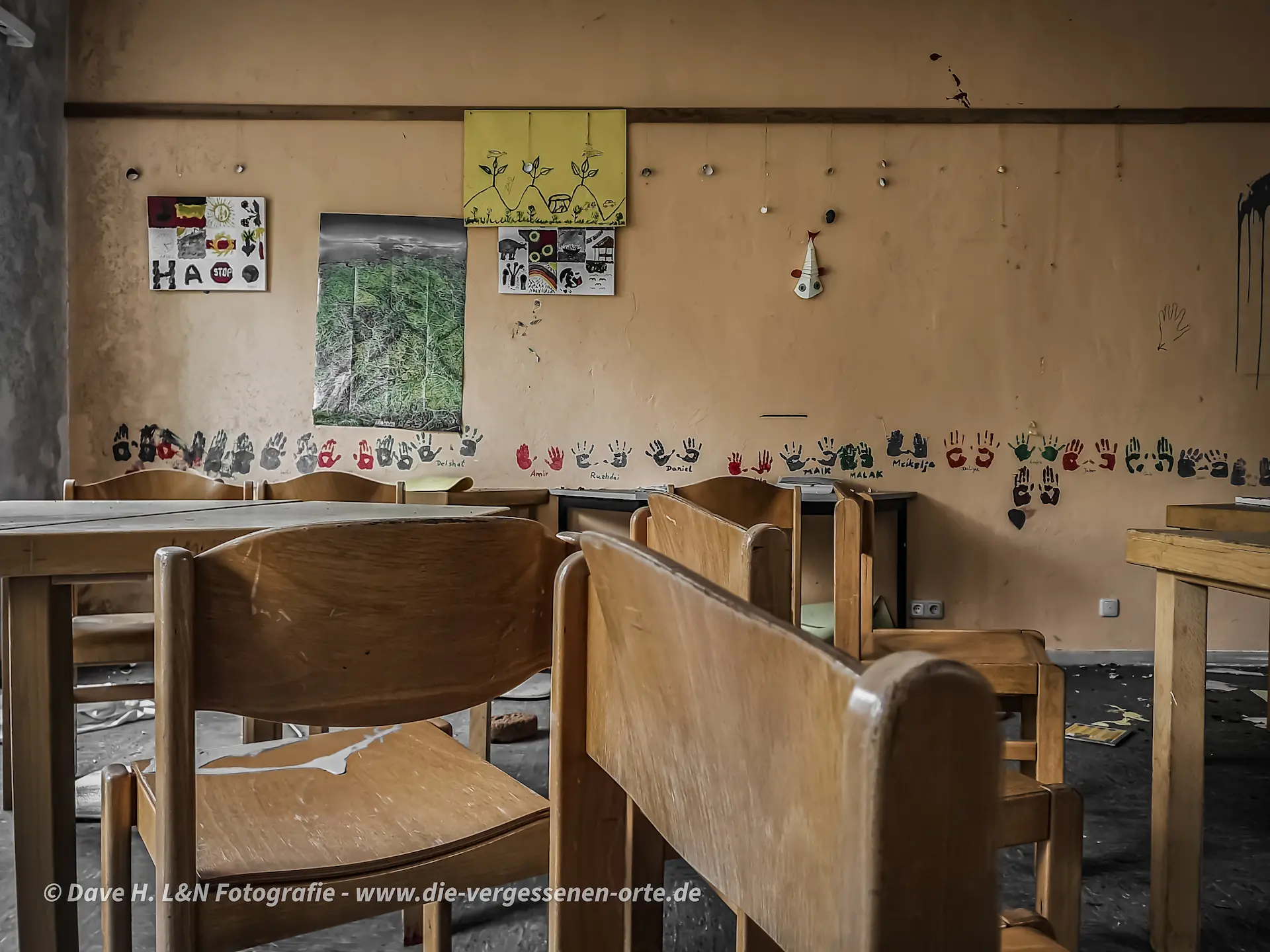Verlassenes Klassenzimmer im Jugenddorf mit Sitzmöbeln und gemalten Kinderbildern – Relikte der Vergangenheit.