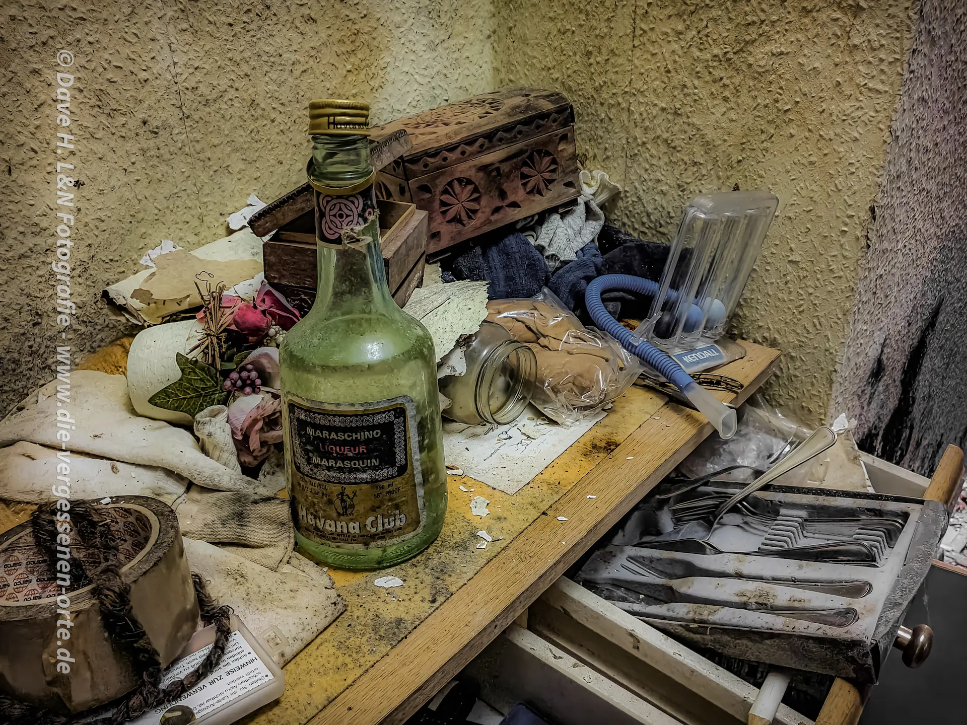 Flasche Likör und altes Besteck auf einem Tisch.