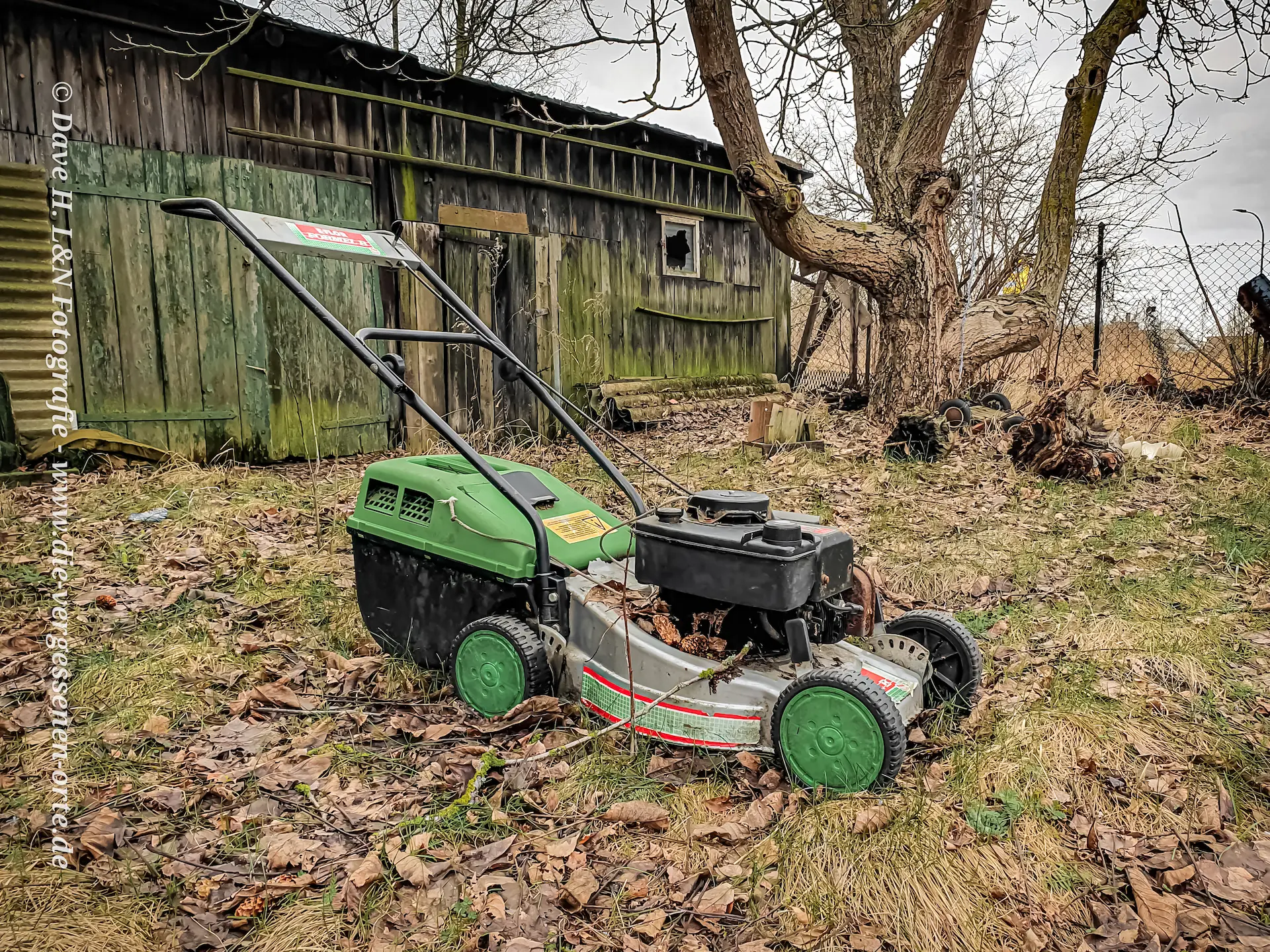 Ein Rasenmäher steht noch im Garten des vergessenen Ortes.