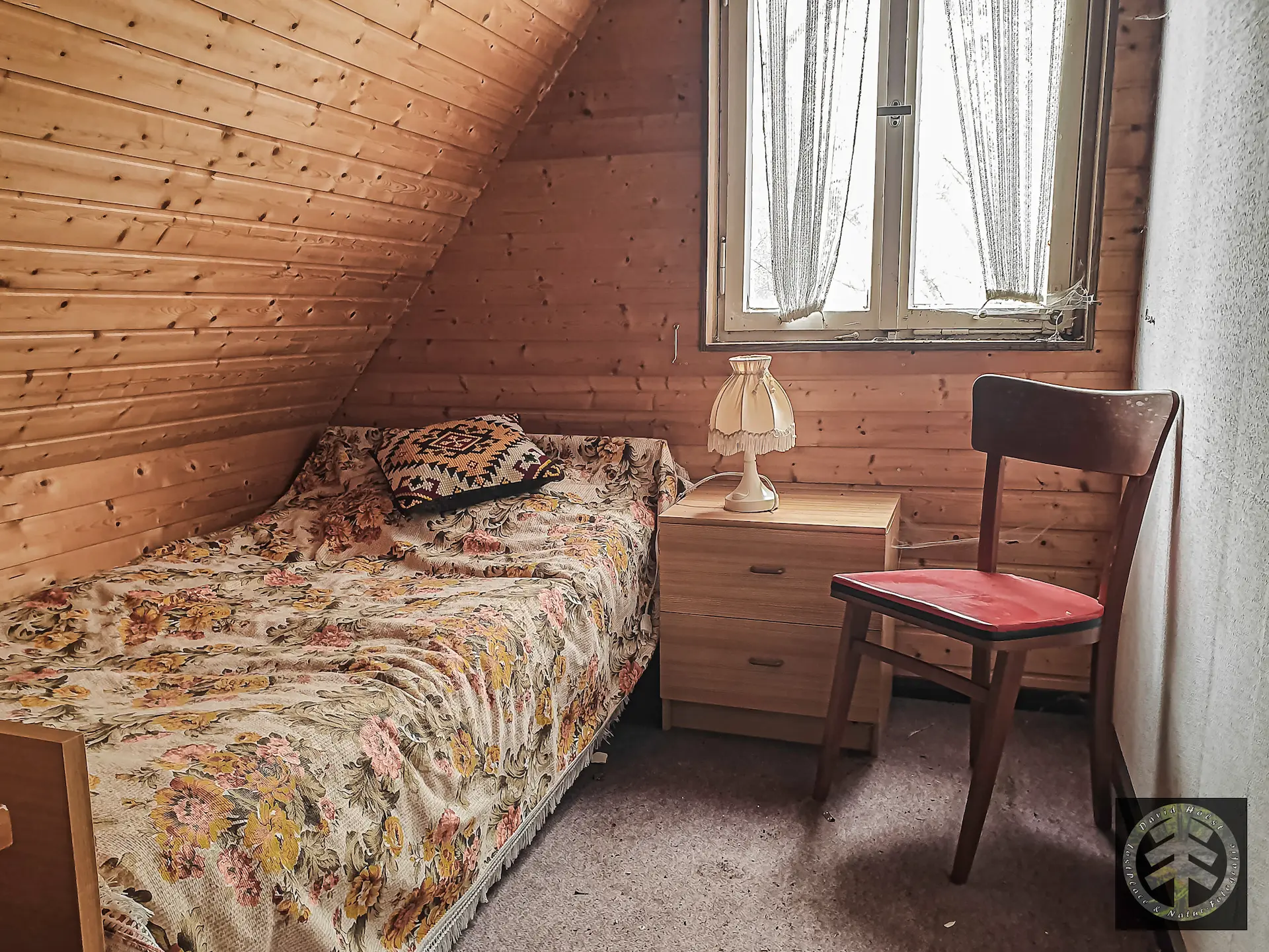 Verlassenes Wochenendhaus: Bett im Gästezimmer mit Nachtschrank.