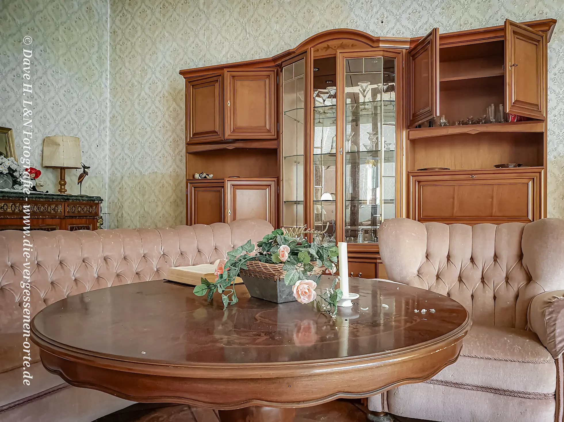 Sitzecke mit rosa Couch und antikem Schrank im verlassenen Schloss.