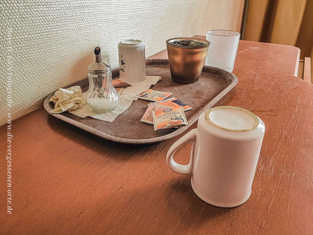 In einem verwaisten Zimmer eines Hotels befindet sich auf dem Tisch noch ein Tablett mit Zucker und Tassen.