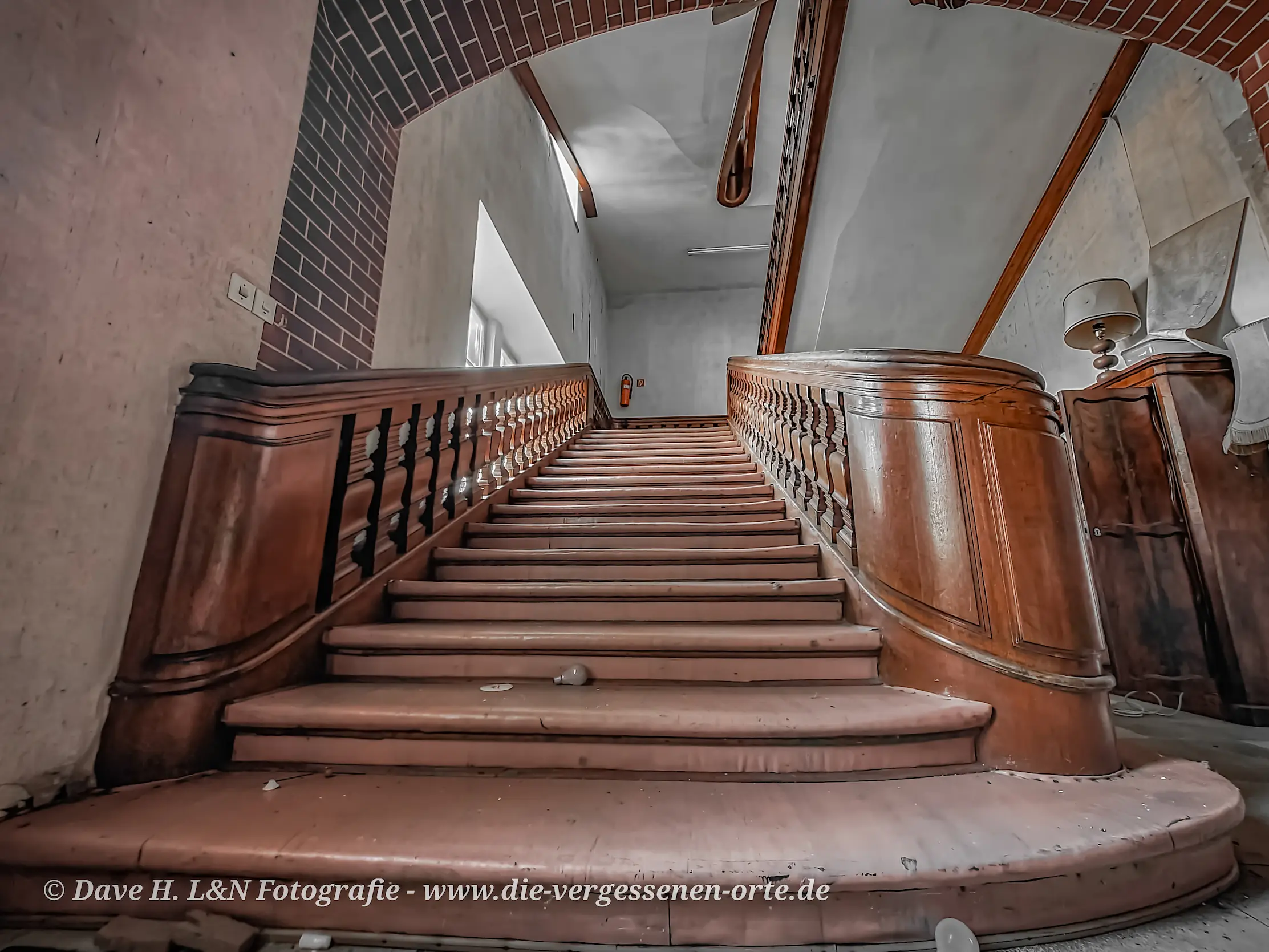 Eine herkömmliche Treppe mit Holzgeländer und Sicht auf den oberen Bereich des Gebäudes.
